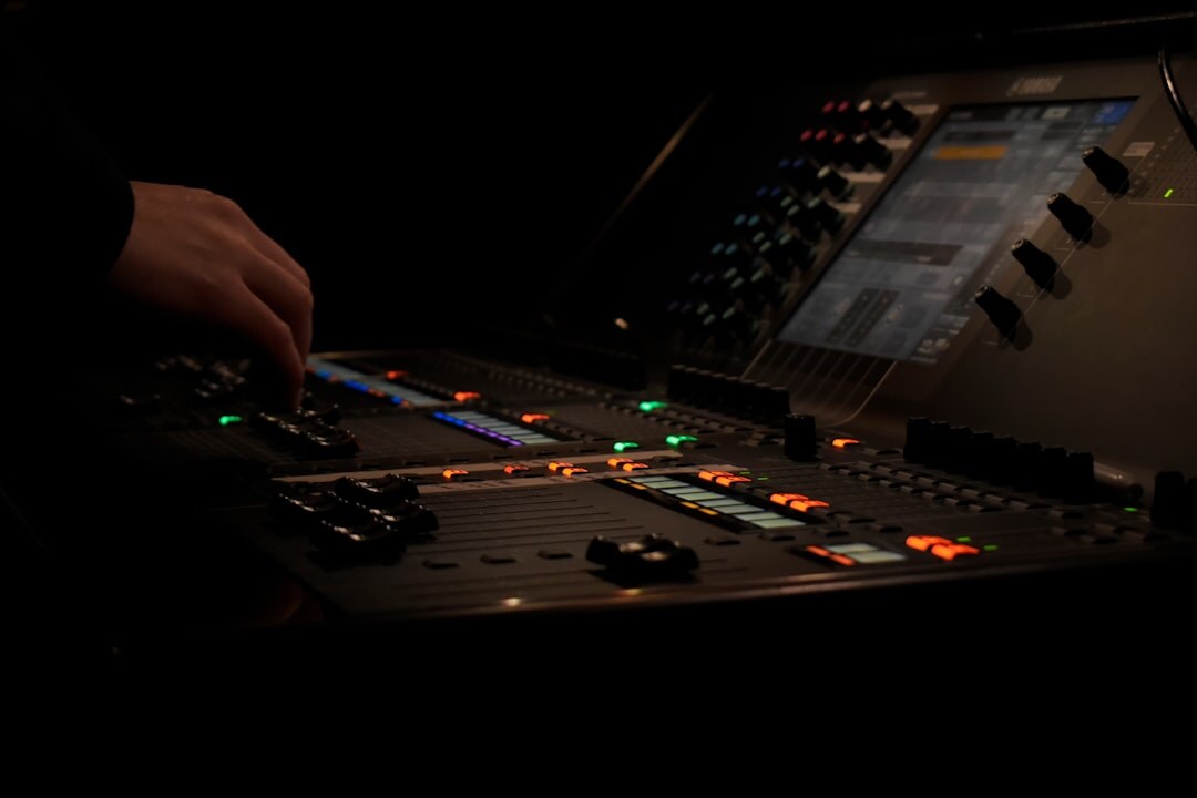 Close up of hands operating a video switcher console with glowing buttons